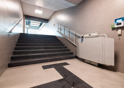 Zdjęcie schodów oraz windy przyschodowej dla niepełnosprawnych.