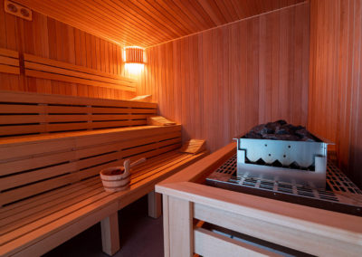 Trzy drewniane ławy w saunarium, po prawej stronie stoi generator pary.